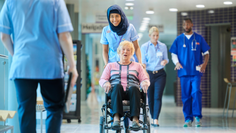 Image of NHS nurse pushing a person in wheelchair